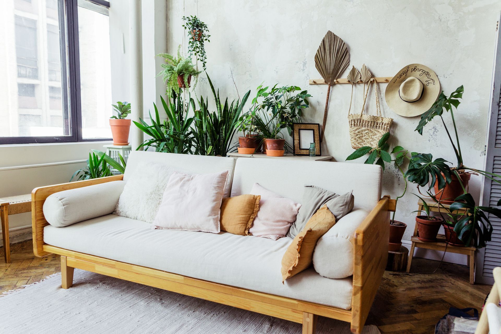 a living room filled with lots of potted plants and a white couch