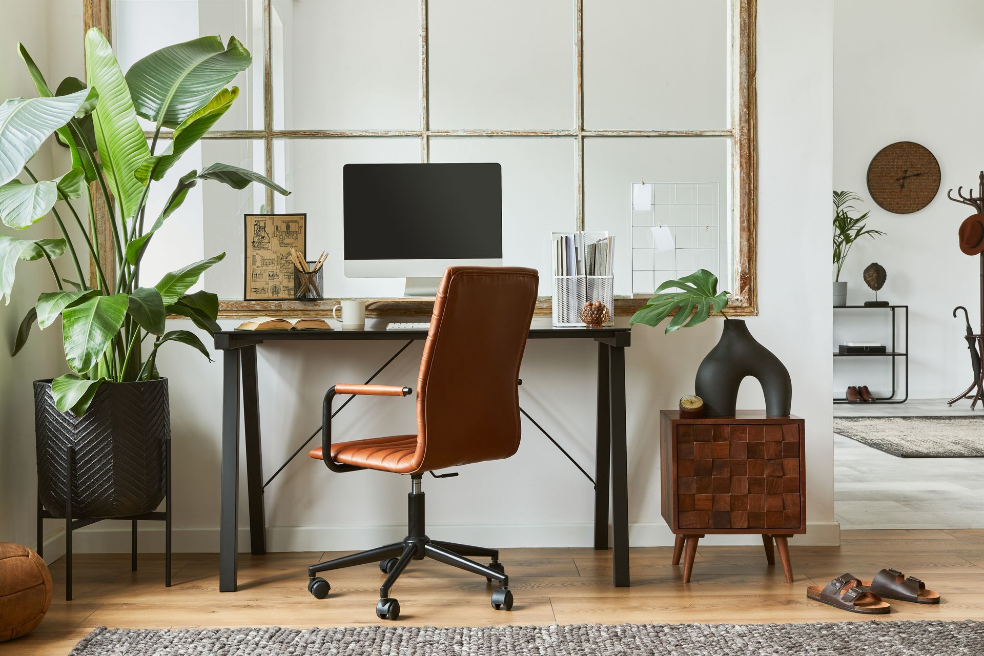 an industrial style office set up, with a desk with metal detailing, a brown leather chair, and a computer on it