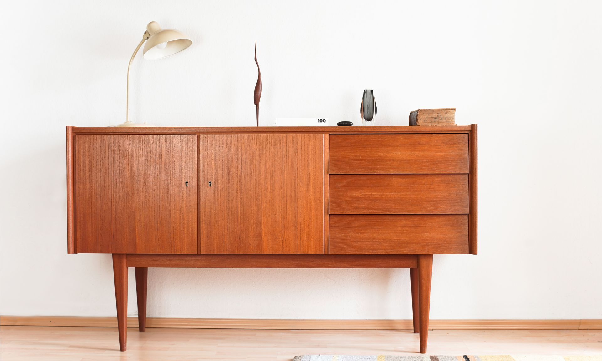 A wooden dresser is sitting in a living room next to a white wall.