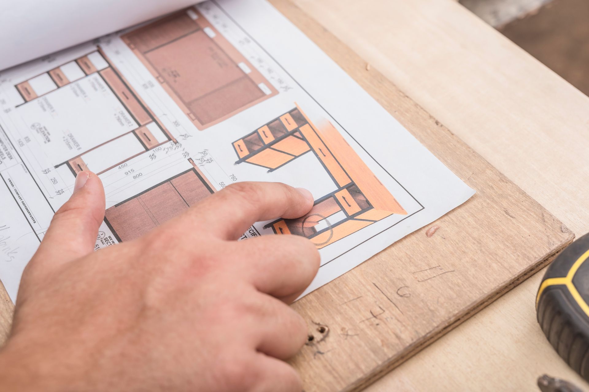 A person is looking at a blueprint of a house on a wooden table - ordering custom furniture