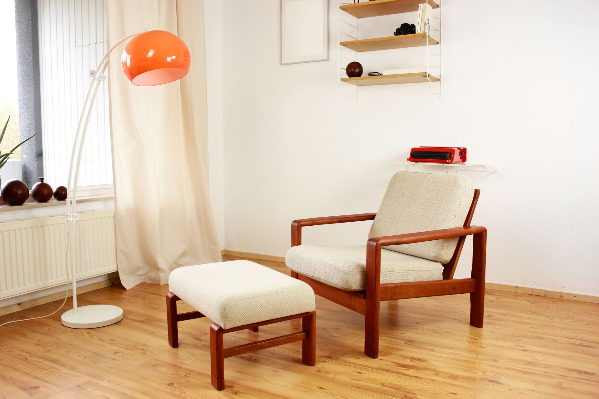 midcentury modern chair and ottoman in a room with a red clock on the wall
