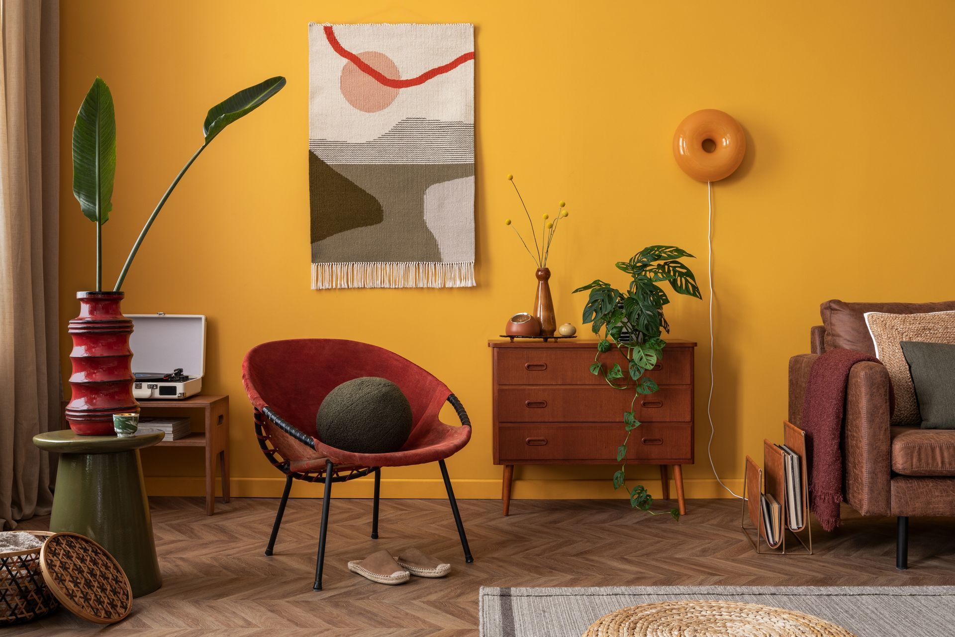 A living room with yellow walls , a red chair , a couch , a dresser and a record player. color psychology