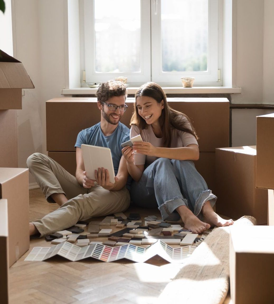 A man and a woman are sitting on the floor looking at sample materials for custom furniture