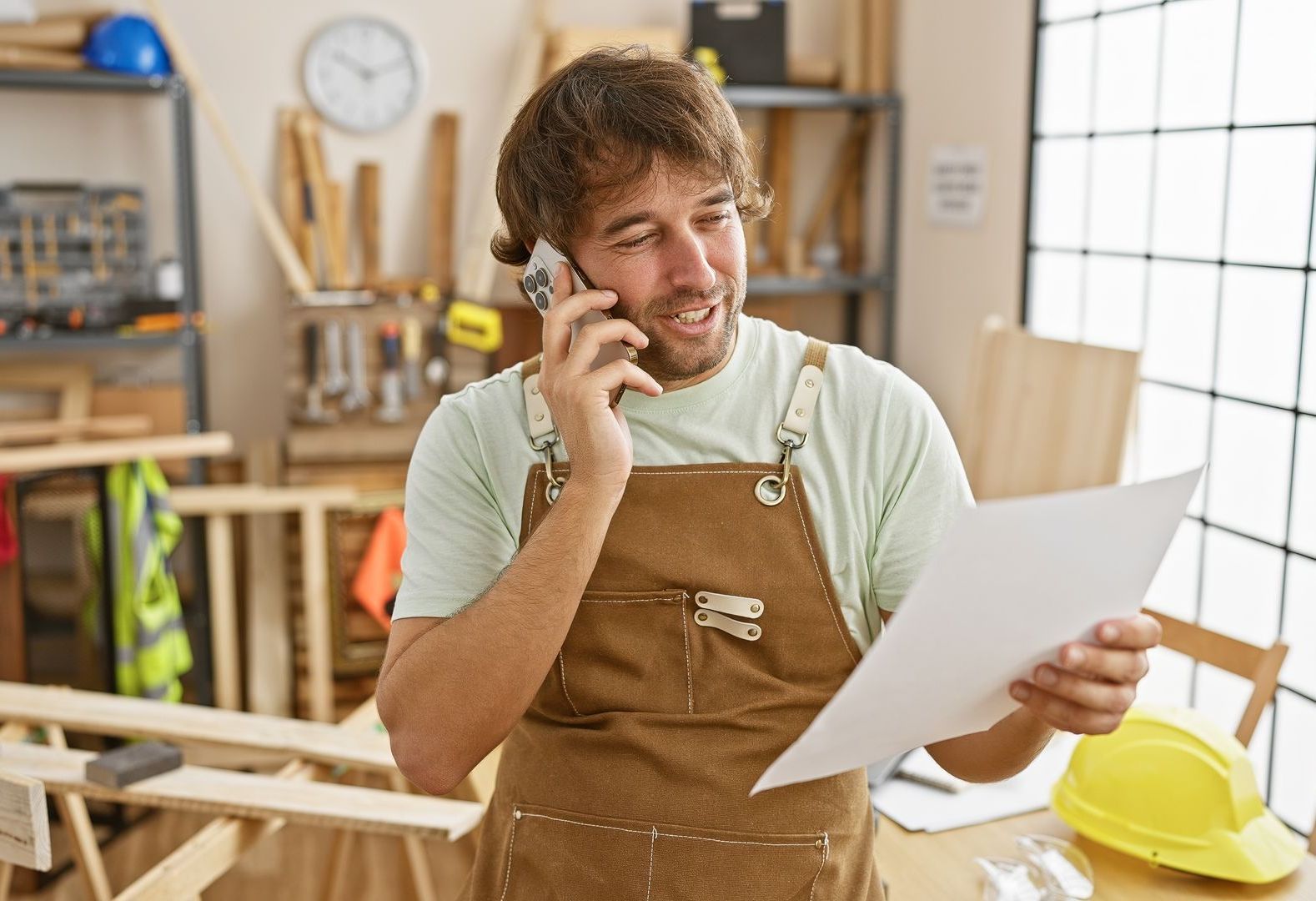 A custom furniture manufacturer is talking on a cell phone with an interior designer about custom furniture design