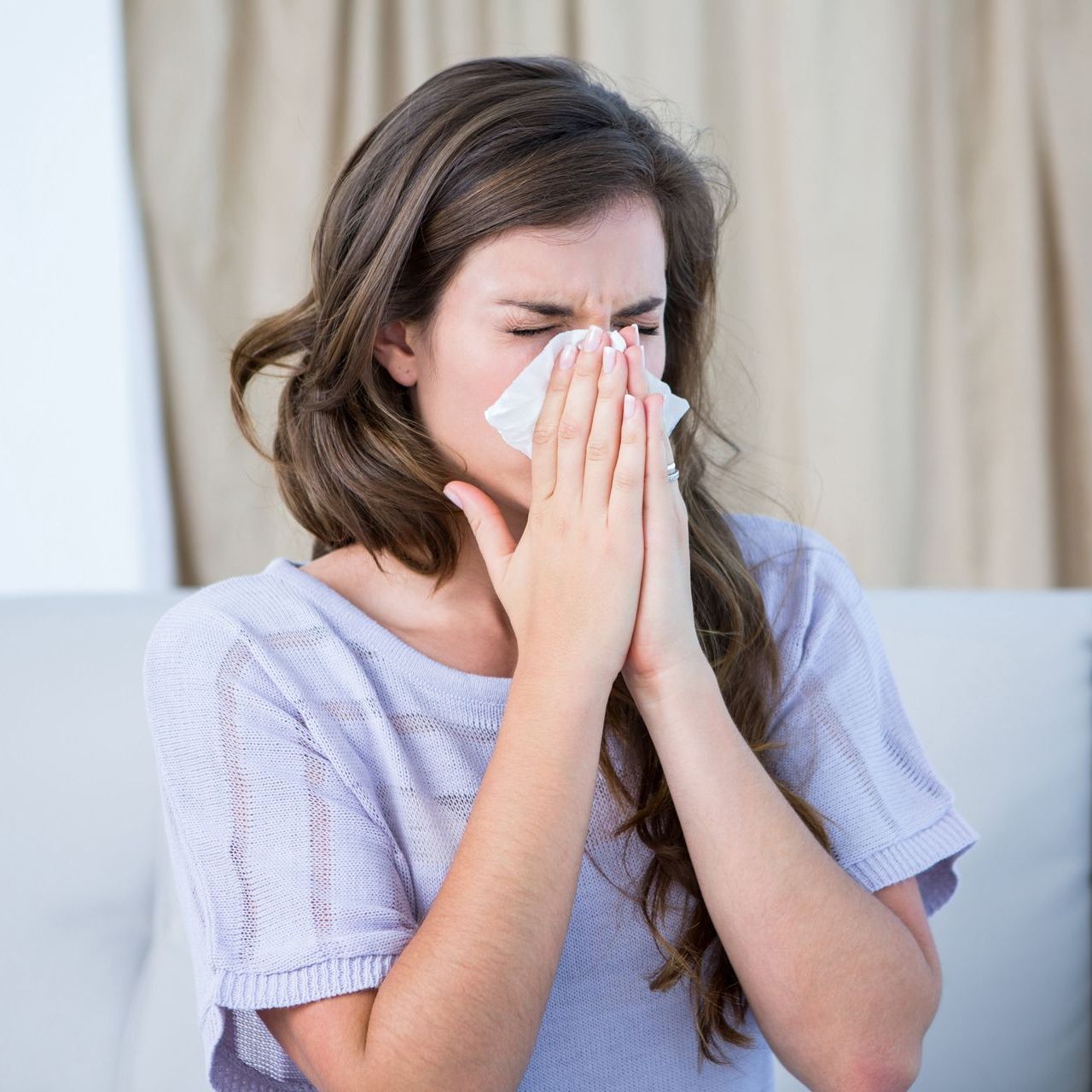 A woman blowing her nose into a tissue