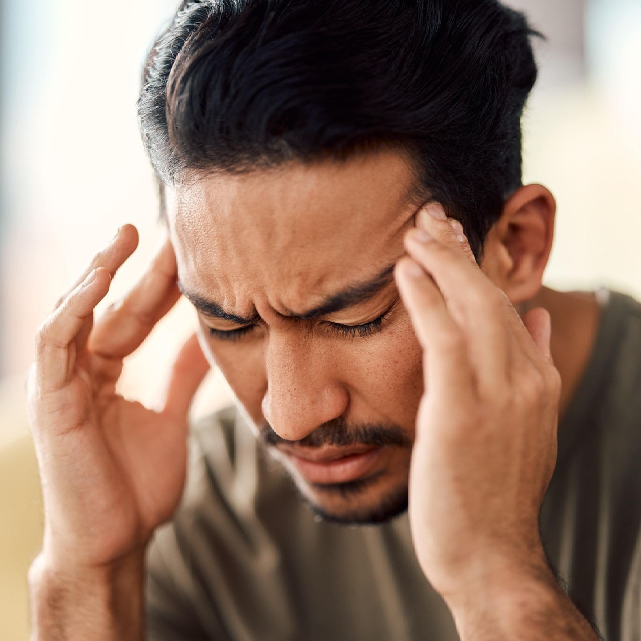 A man with a beard is holding his head