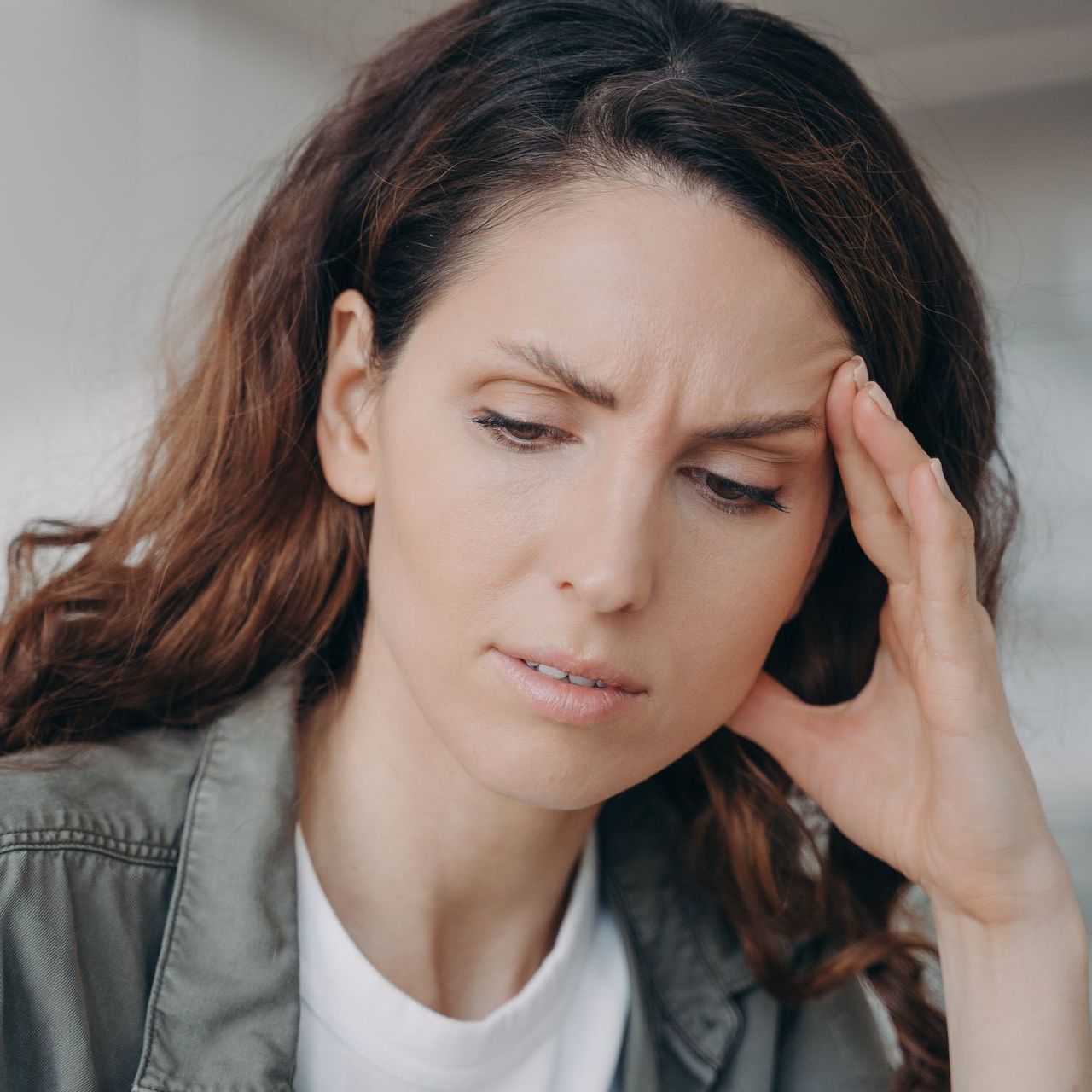 A woman looking down whole holding her head in confusion