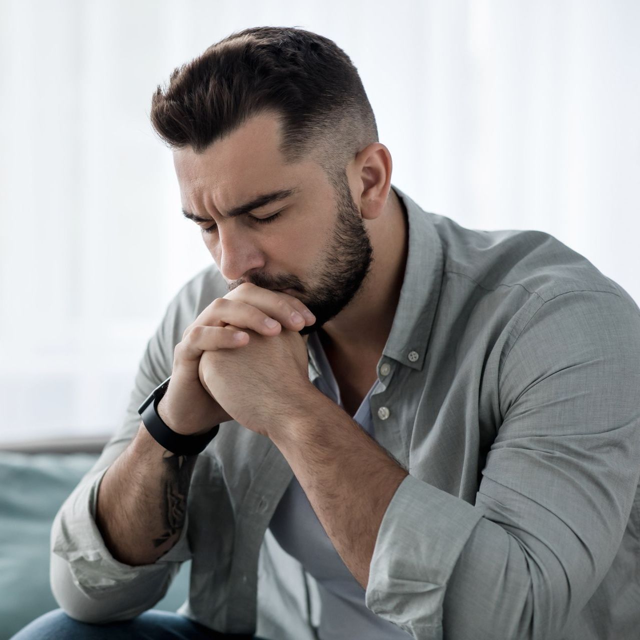 A man looking upset while gazing down and holding his hands to his face