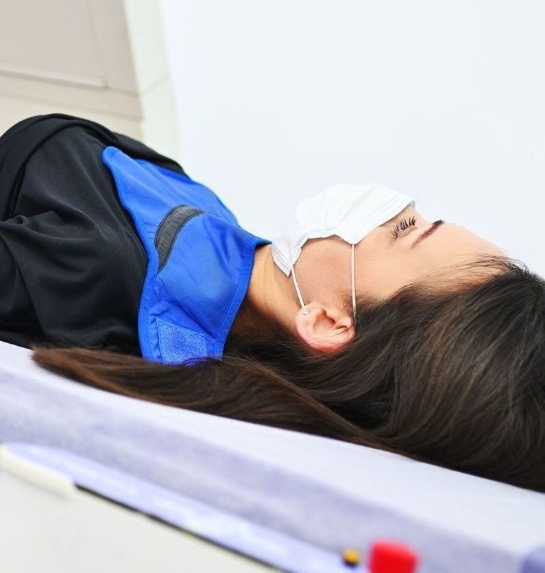 A woman is laying on a bed getting an x-ray