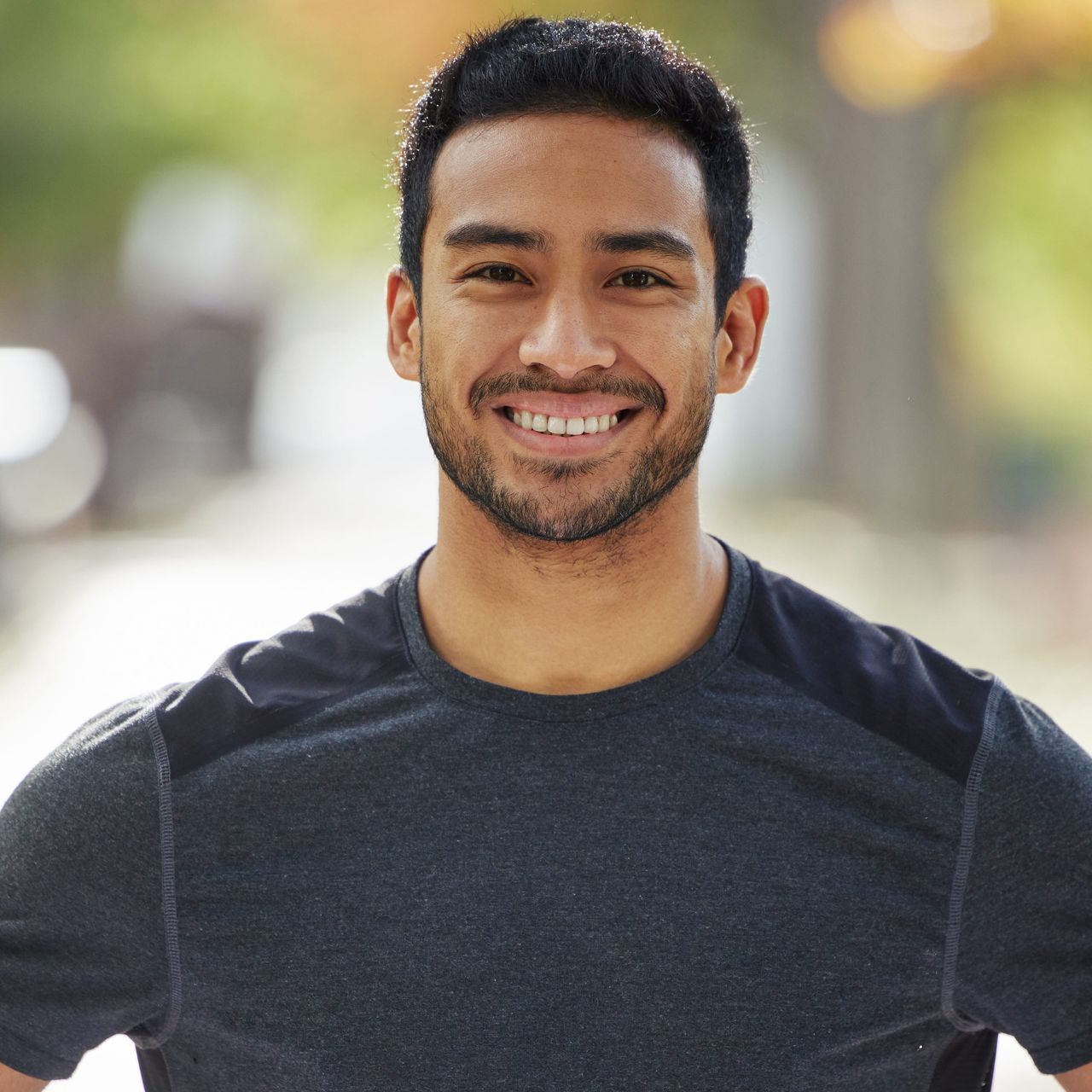 A man with a beard is smiling for the camera while wearing a gray shirt