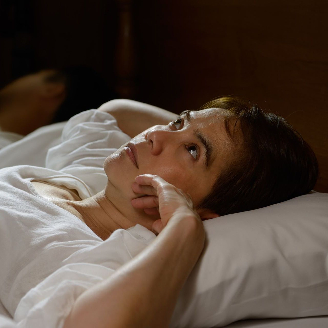 A woman lying awake in bed and staring at the ceiling