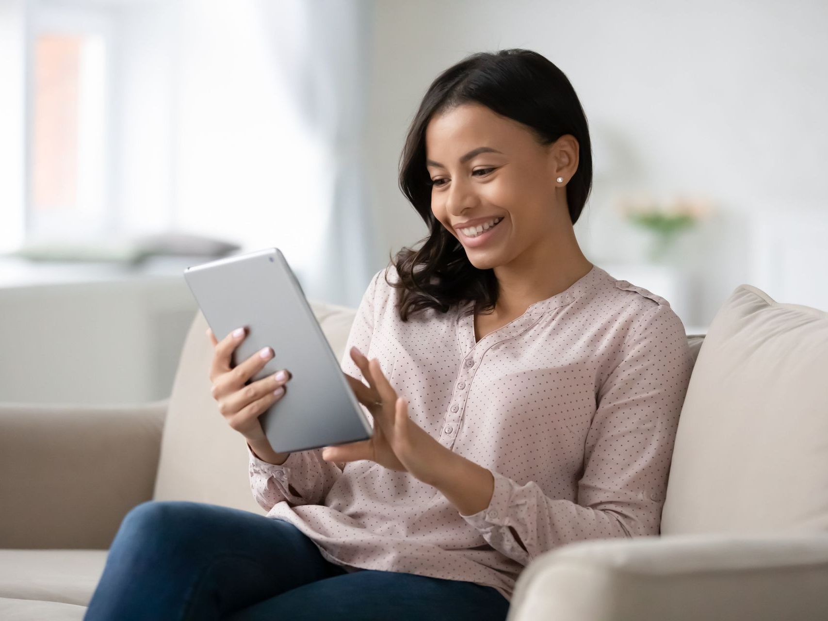 A woman smiling while reading on a tablet