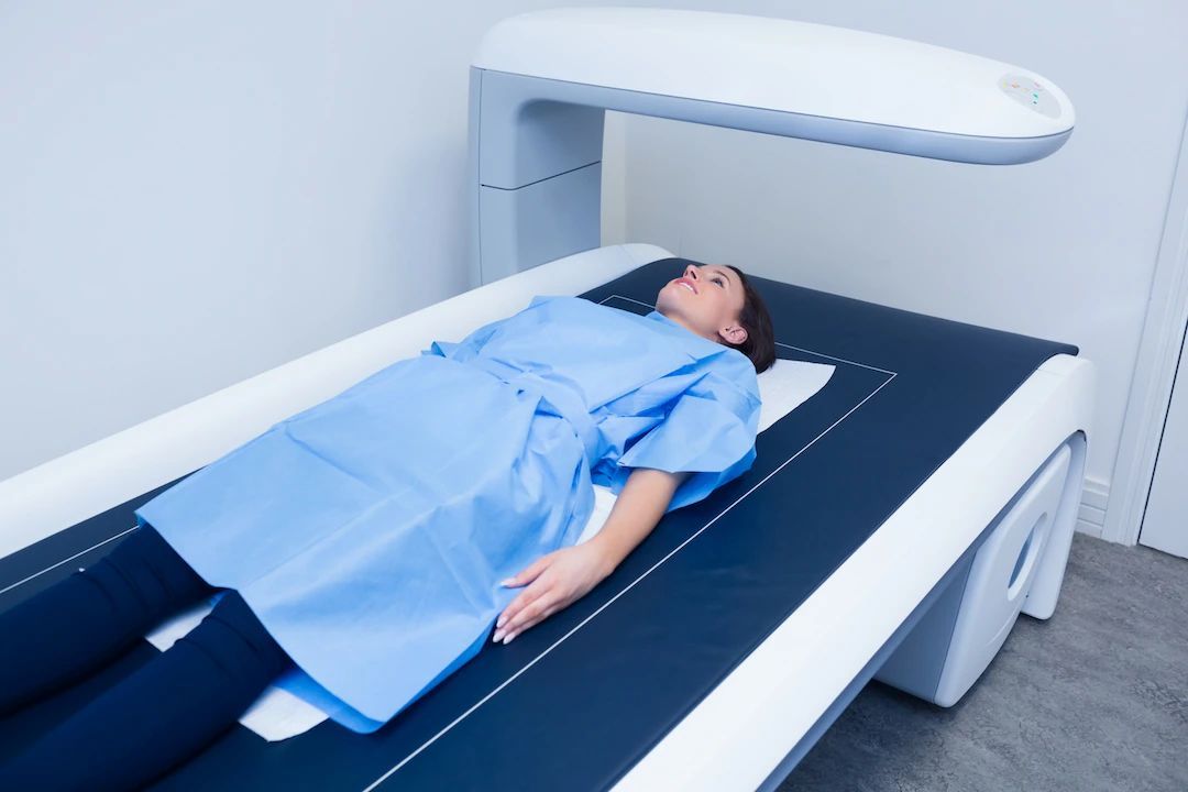 A woman is laying on a bed getting an x-ray