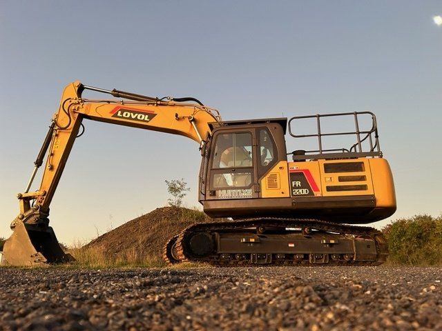 A yellow and black excavator is parked on a gravel road.