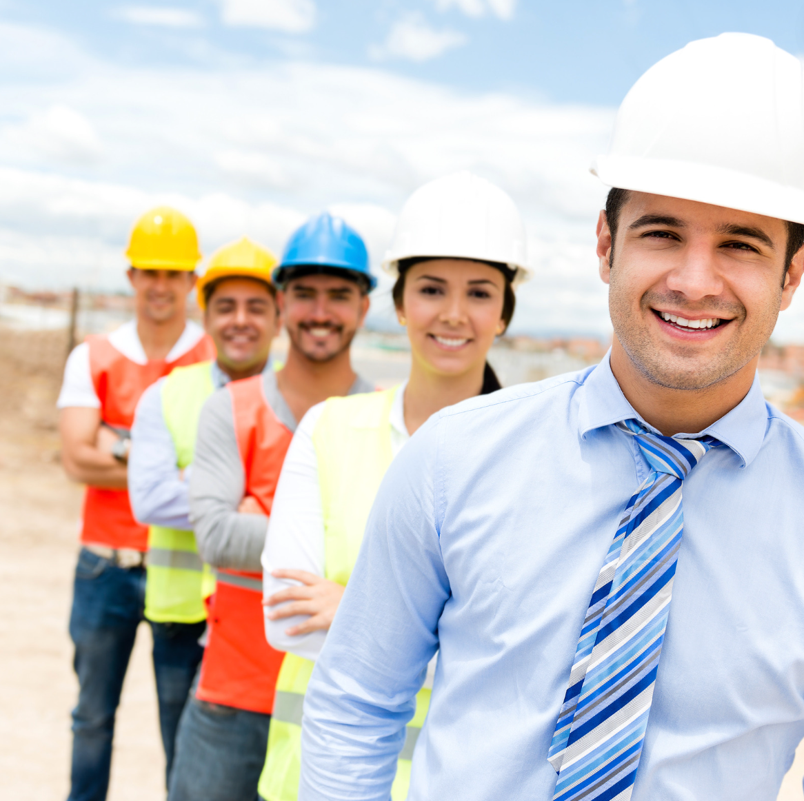 A man wearing a hard hat stands in front of a group of contractors.