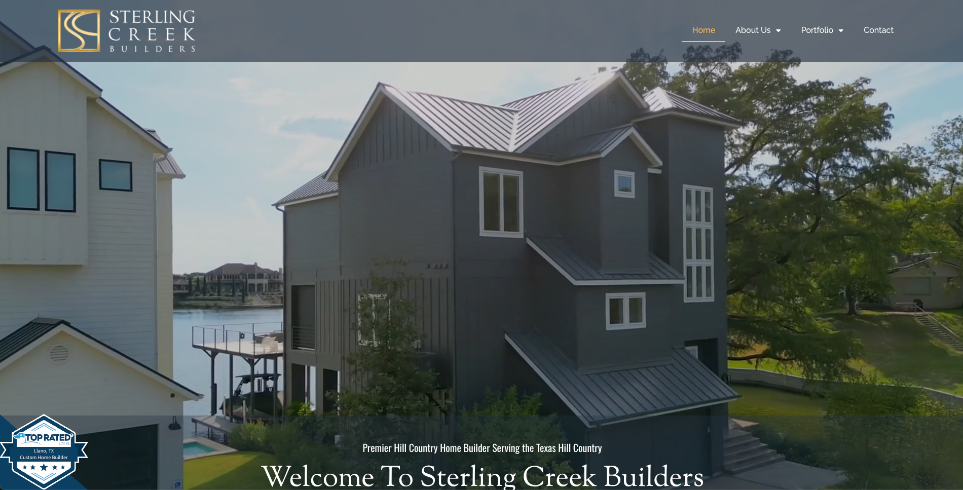 A large house with a metal roof is sitting next to a body of water.