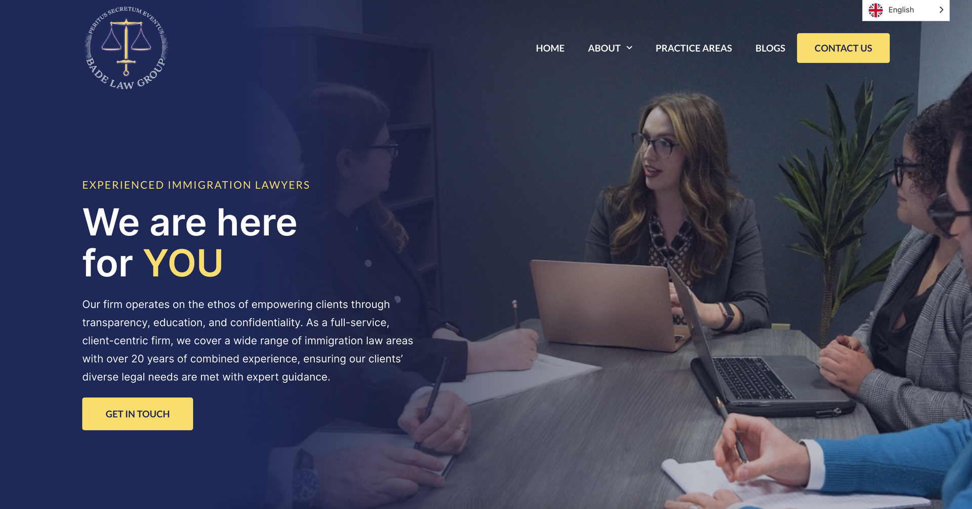 A group of people are sitting around a table with laptops.