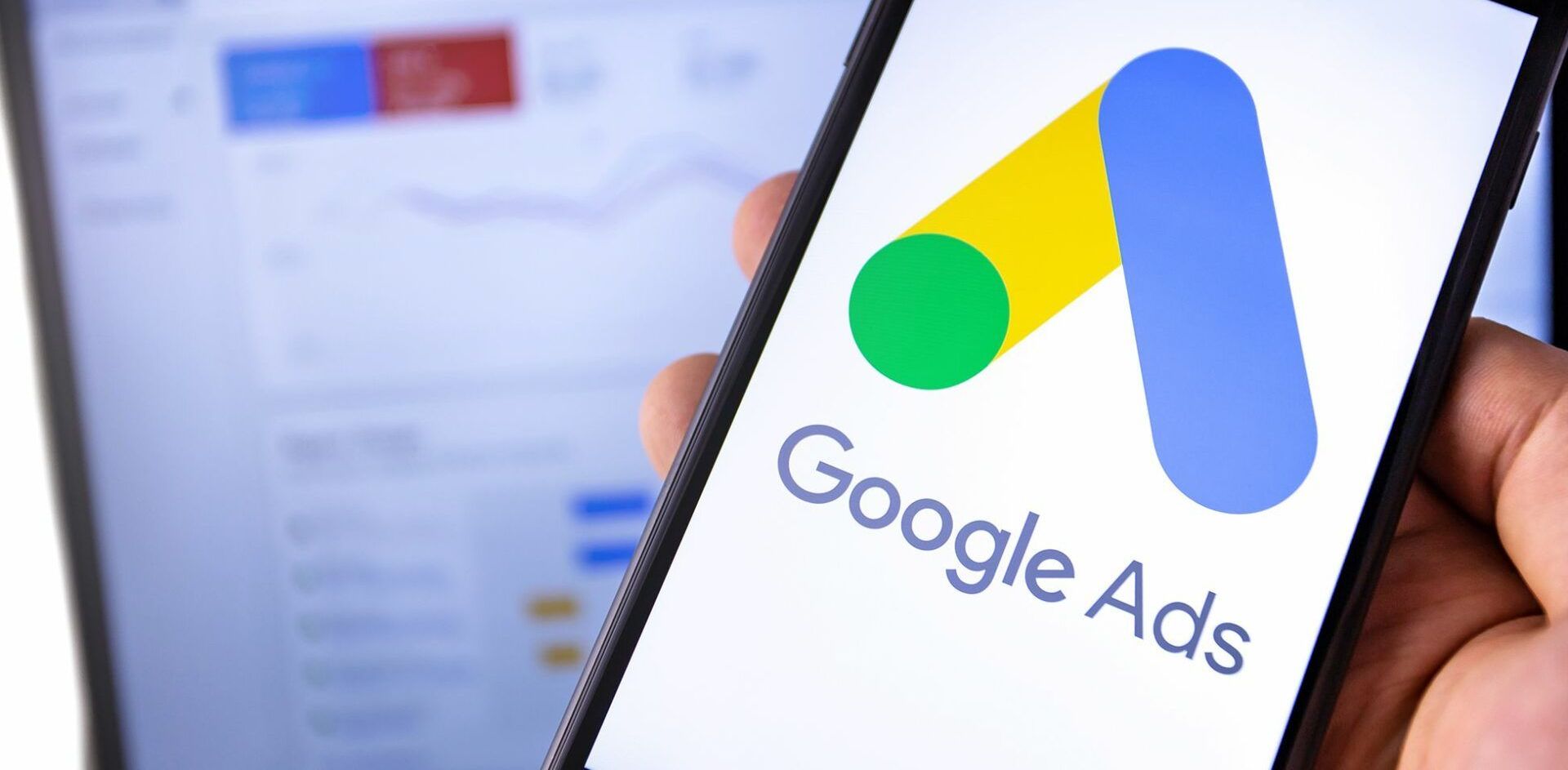 A person is holding a cell phone with the google ads logo on it.