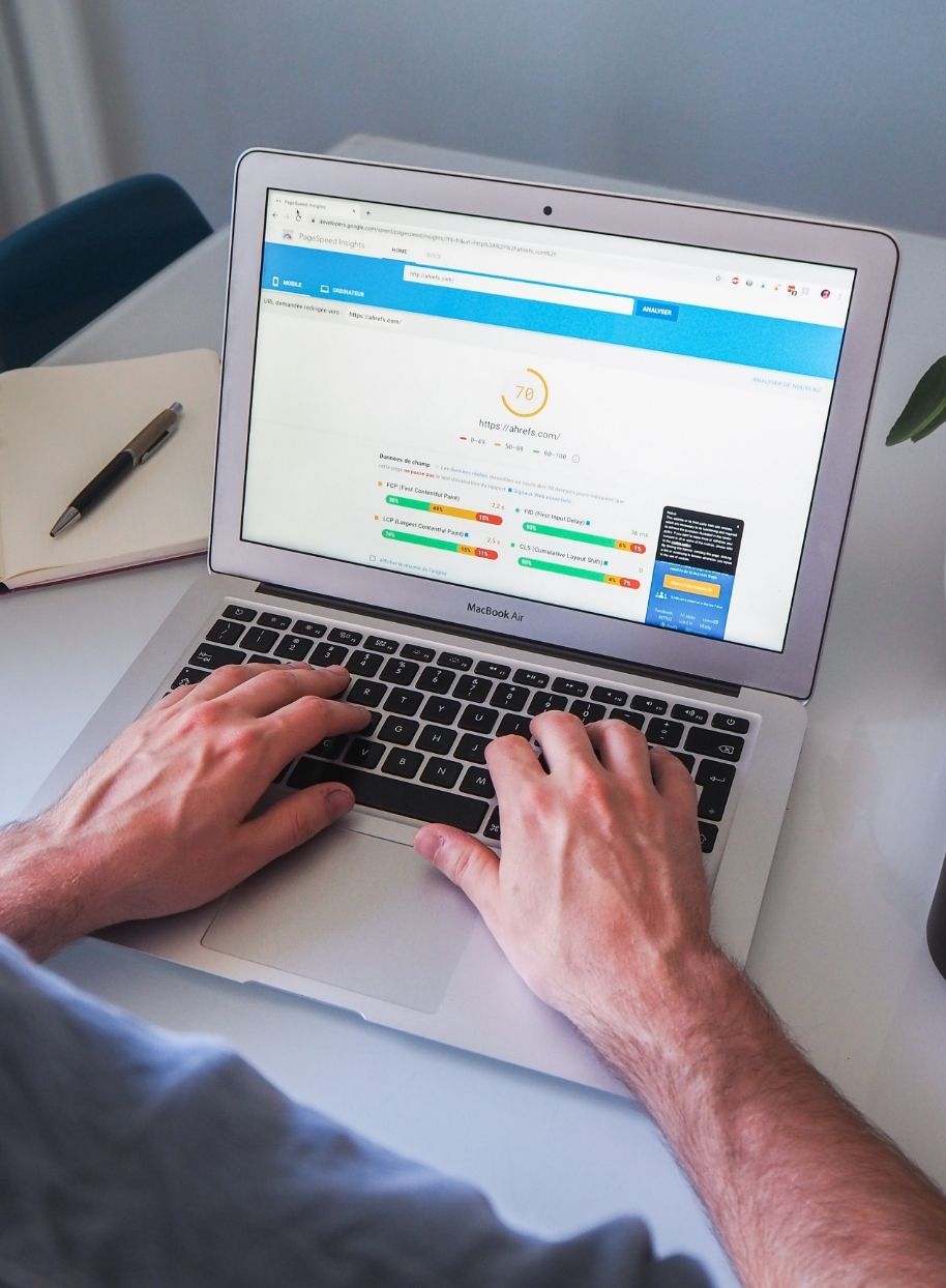 A person is typing on a laptop computer scoring the seo of a website.