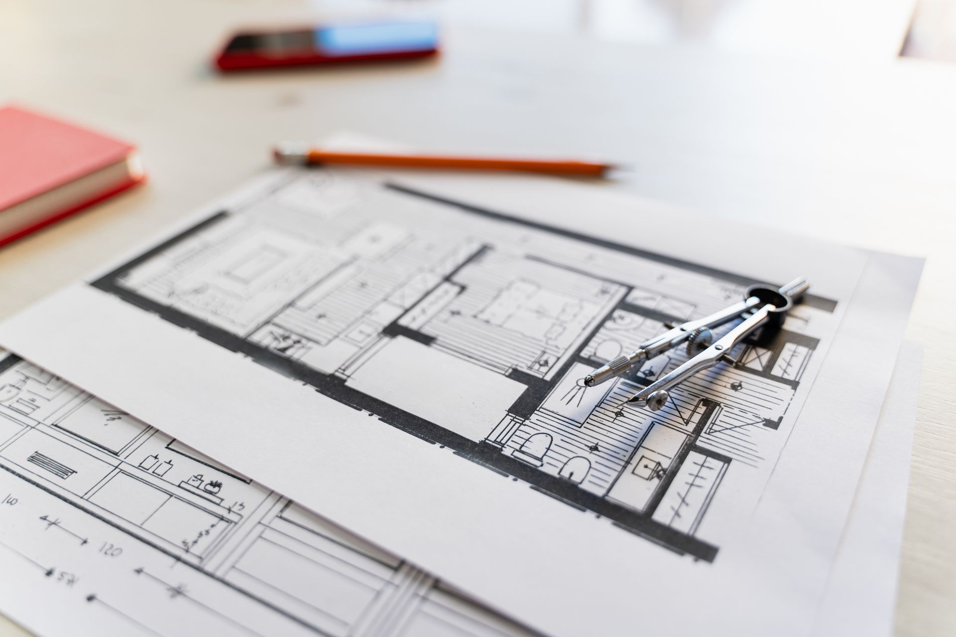 Architectural blueprints and engineering tools on an architect's desk.