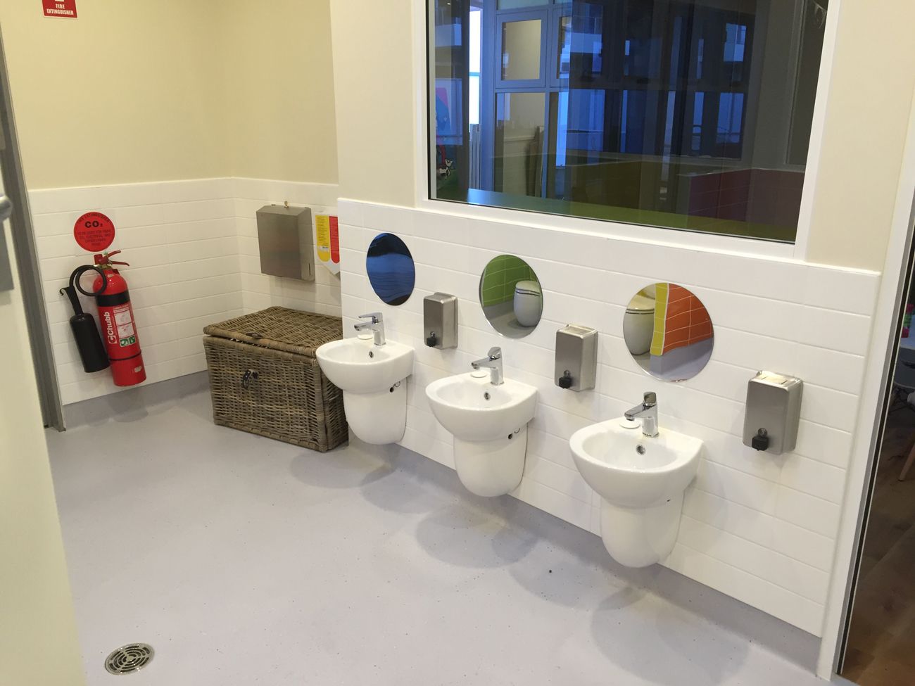 A bathroom with three sinks and a fire extinguisher