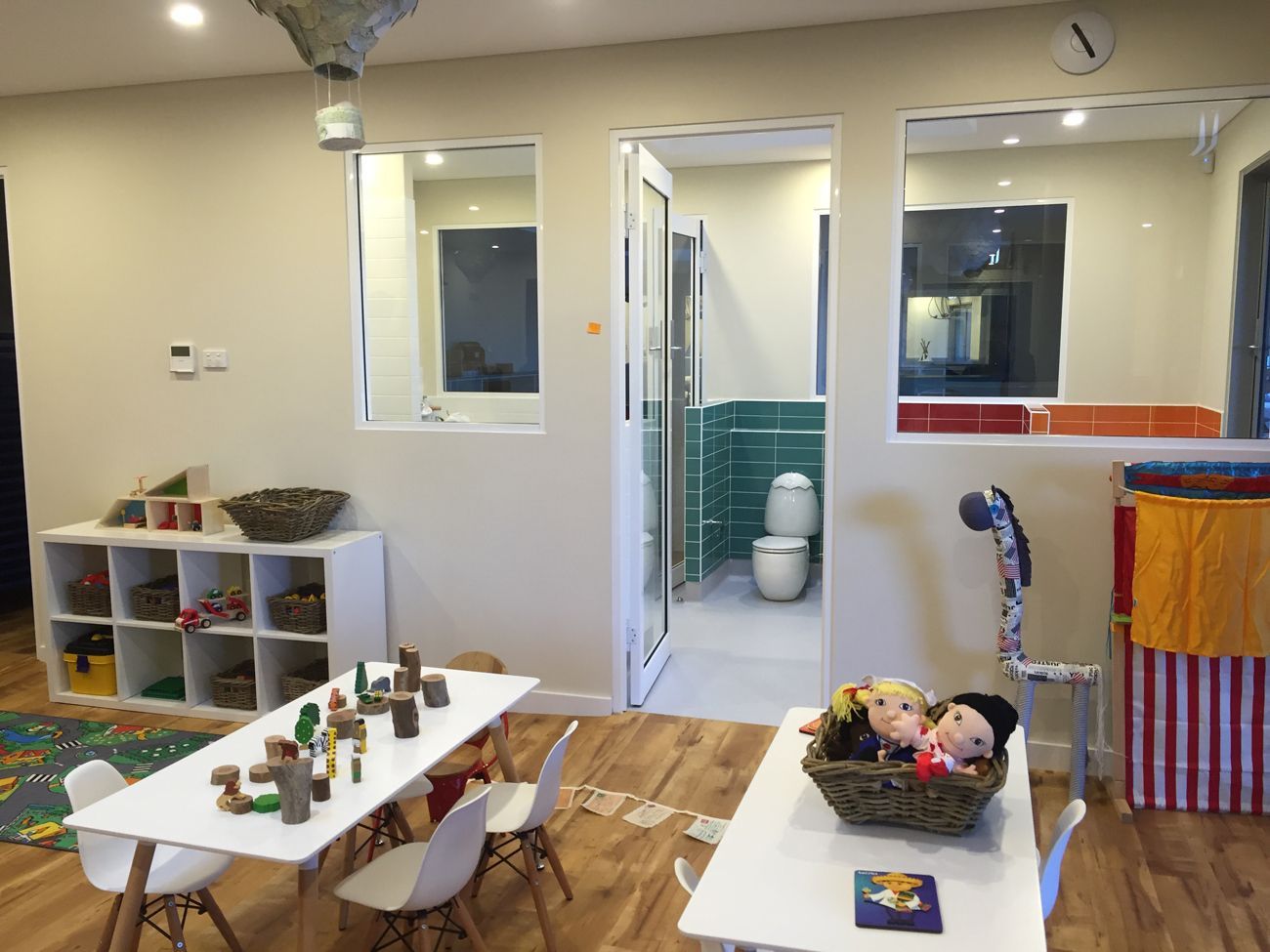 A room with tables and chairs and a toilet in the background