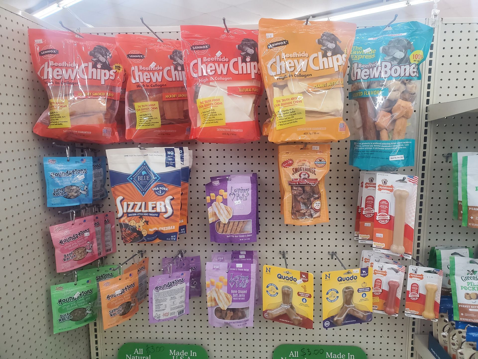 A variety of dog treats are hanging on a wall in a store.