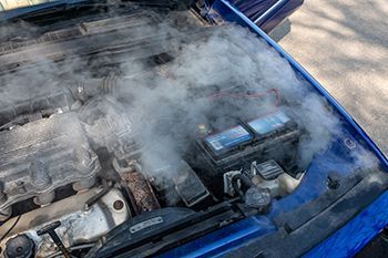 Smoke is coming out of the hood of a car.