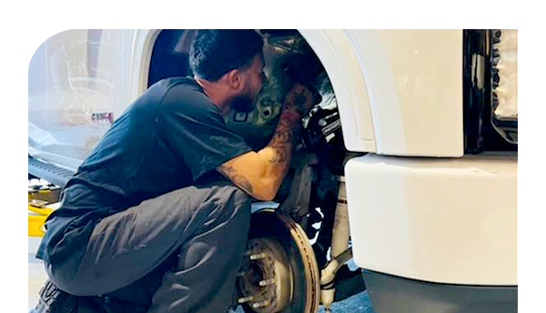 A man is working on a truck in a garage.