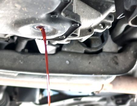 A close up of a car engine with red liquid pouring out of it.