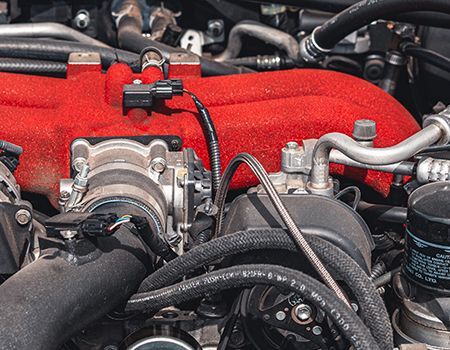 A close up of a car engine with a red hood.