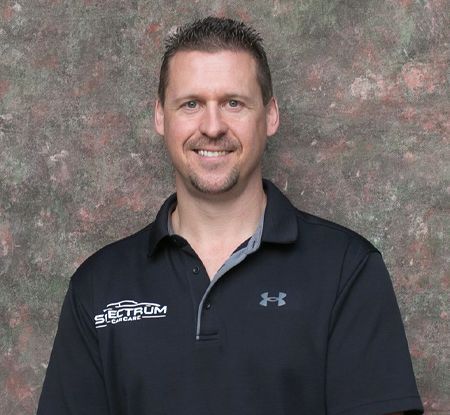 A man wearing a black under armour shirt is smiling for the camera.