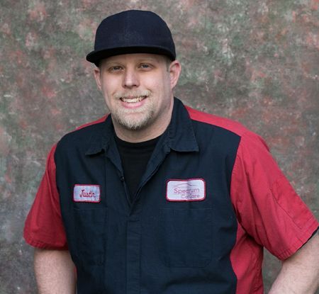 A man wearing a hat and a red and black shirt is smiling for the camera.