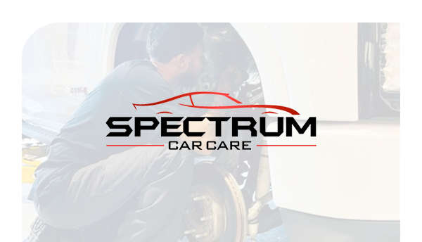 The logo for spectrum car care shows a man working on a car.