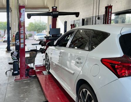 A white car is sitting on a lift in a garage.