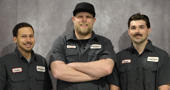 Three men are standing next to each other with their arms crossed.