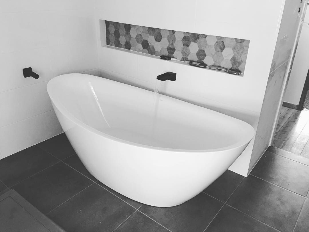 A Man Is Working on A Brick Wall in A Room with A Ladder — Medowie Plumbing & Gas In Medowie, NSW