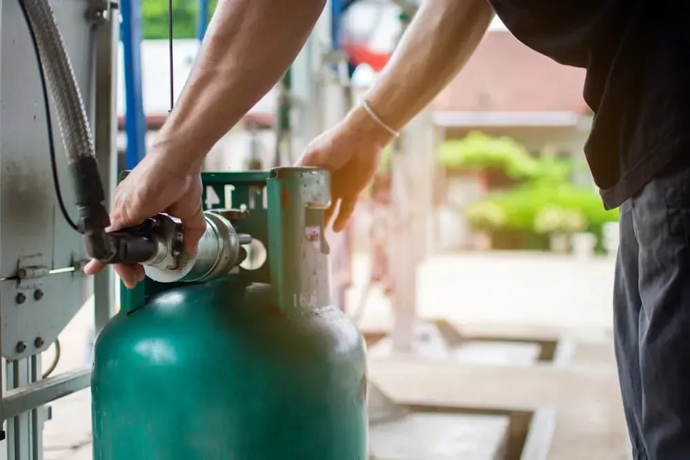 A Man Is Filling a Gas Cylinder with Gas — Medowie Plumbing & Gas In Medowie, NSW