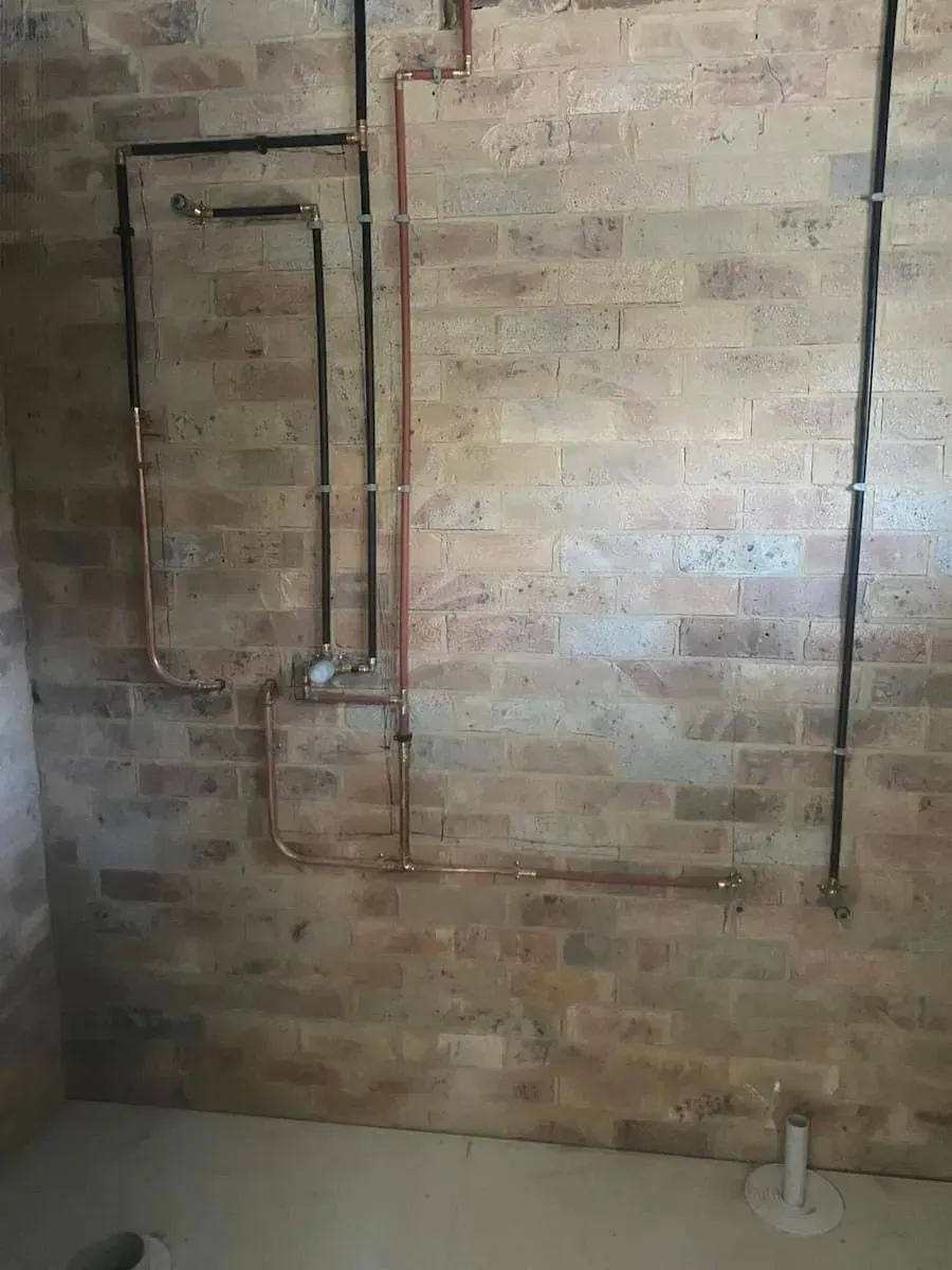 A Bathroom with A Brick Wall and Copper Pipes — Medowie Plumbing & Gas In Medowie, NSW
