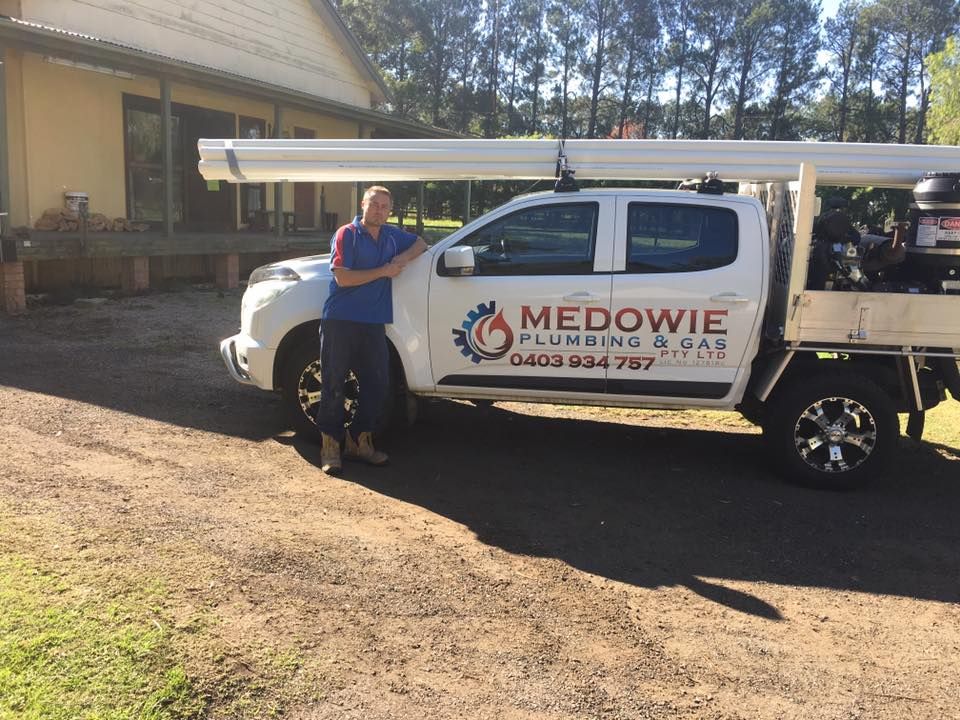 A Man Is Standing Next to A Truck — Medowie Plumbing & Gas In Port Stephens, NSW
