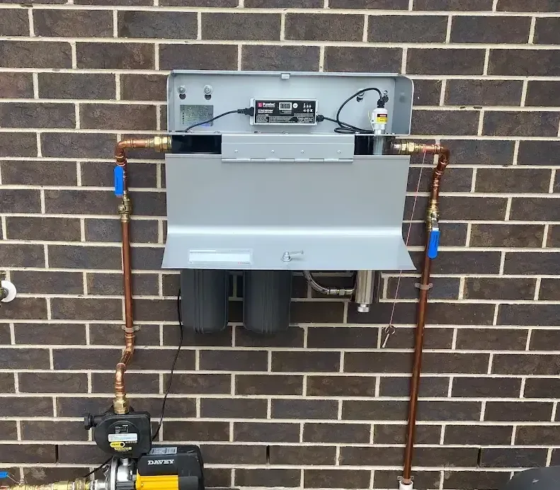 A Hot Water Pump Is Attached to A Brick Wall — Medowie Plumbing & Gas In Medowie, NSW