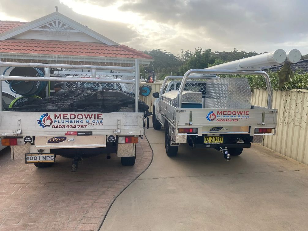 Two Trucks Are Parked in A Driveway Next to A House — Medowie Plumbing & Gas In Medowie, NSW