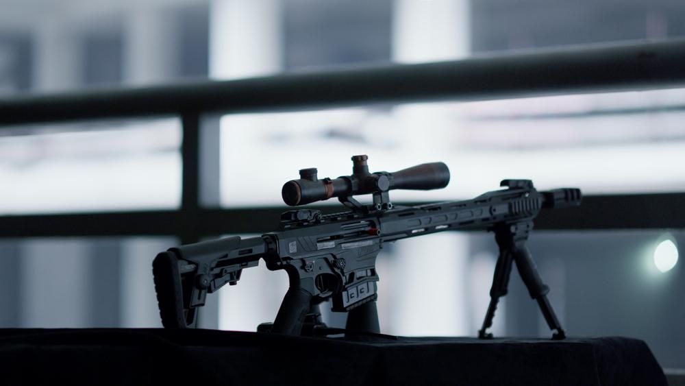 A Scoped Rifle is Positioned on a Table — Coffs Coast Firearms In Coffs Harbour, NSW