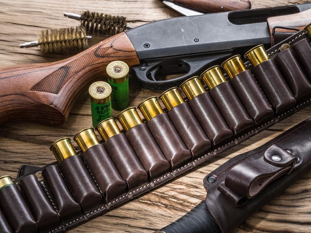 A Shotgun and Rifle With Ammunition Displayed on a Wooden Table — Coffs Coast Firearms In Coffs Harbour, NSW