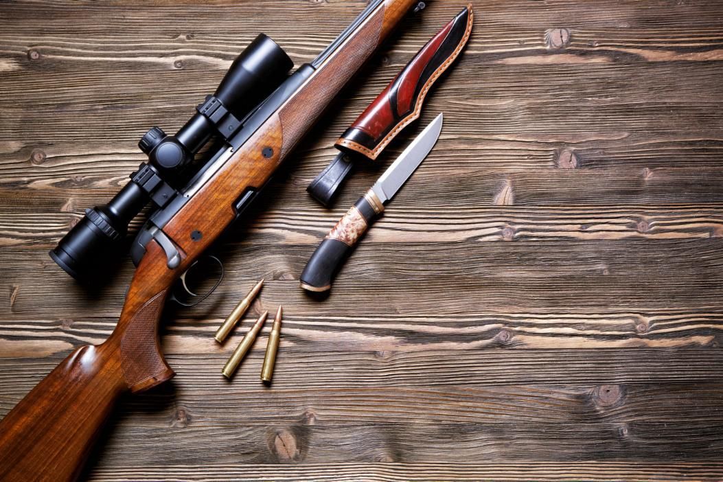 A Rifle and a Knife Are Placed on a Wooden Table — Coffs Coast Firearms In Coffs Harbour, NSW