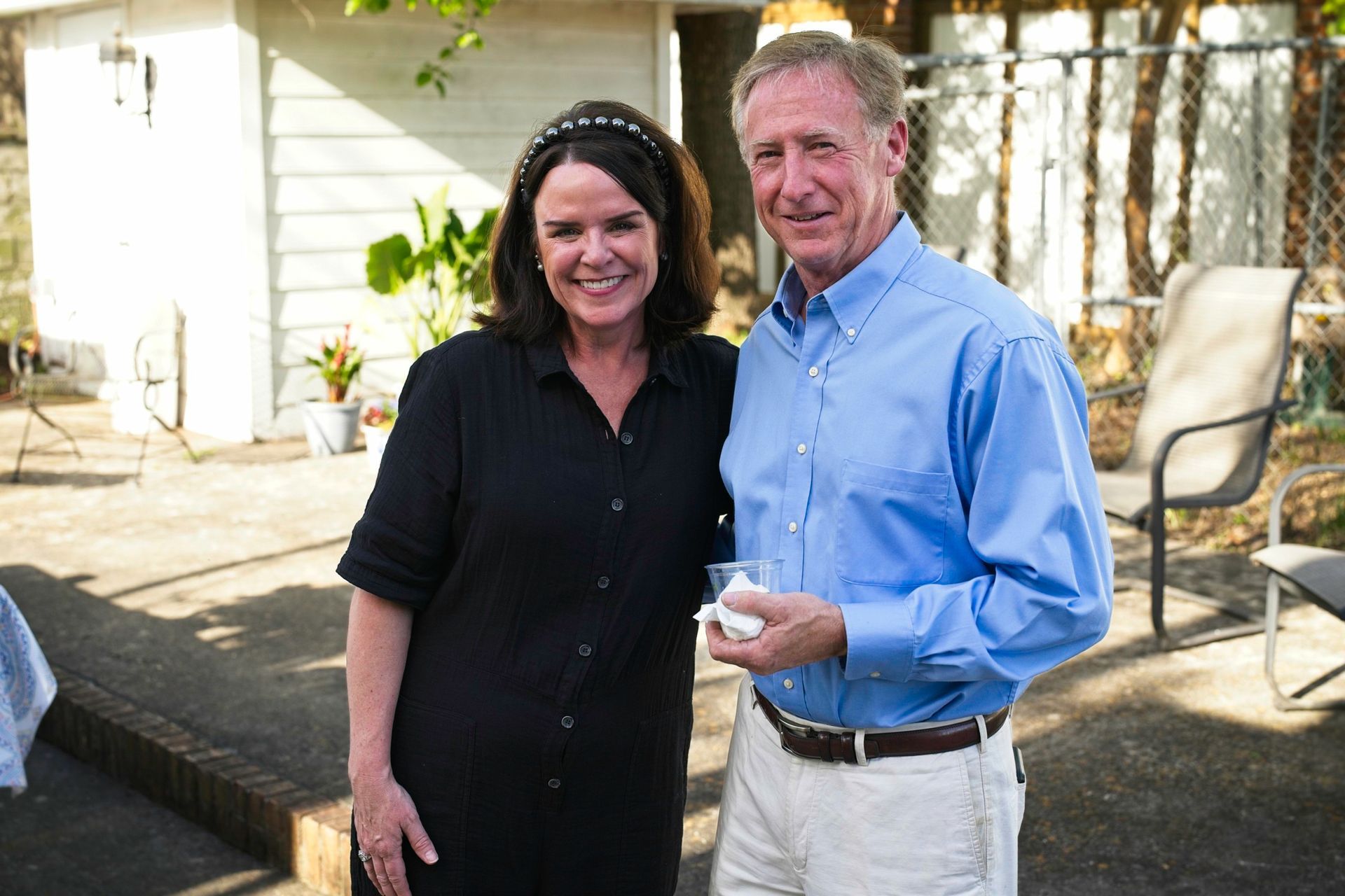 A man and a woman are posing for a picture in front of a house.