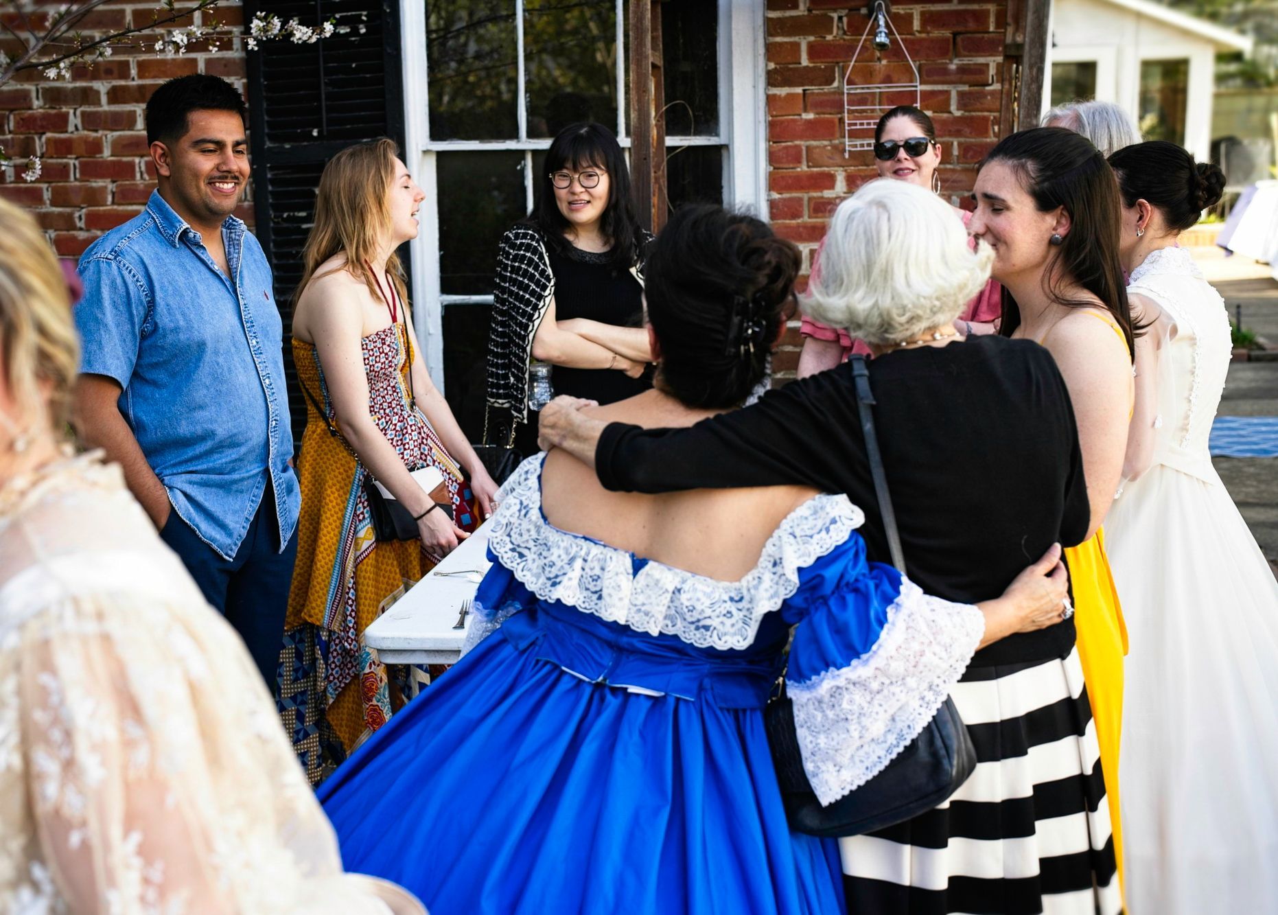 A woman in a blue dress is hugging another woman