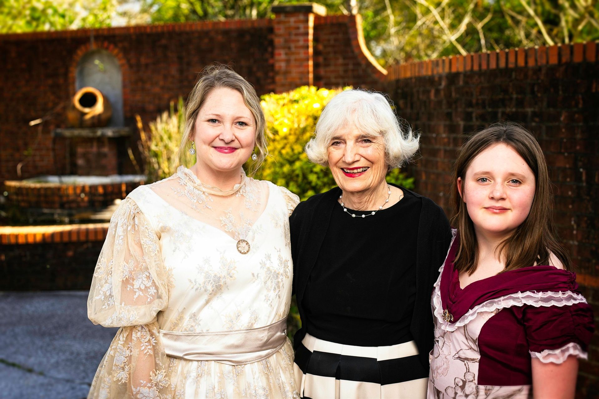 Three women are posing for a picture together in front of a fountain.