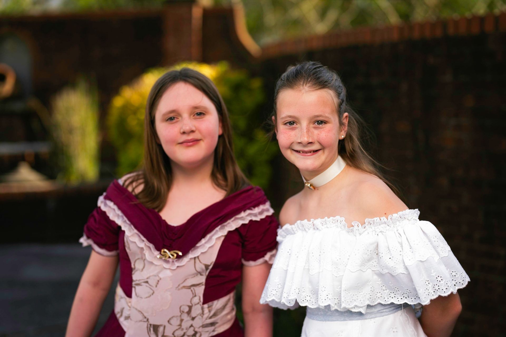 Two young girls in dresses are posing for a picture.