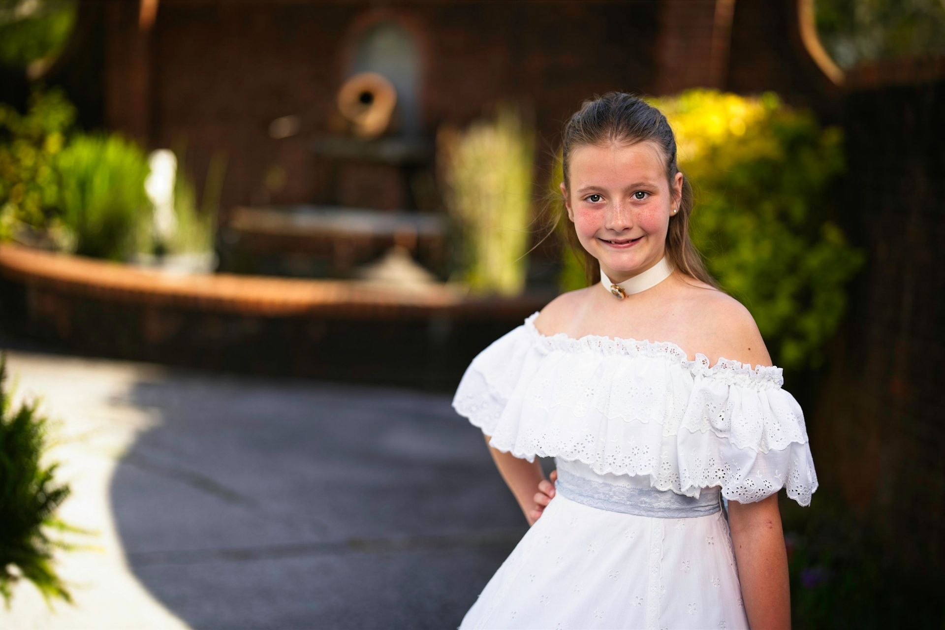 A young girl in a white dress is standing in front of a gazebo.